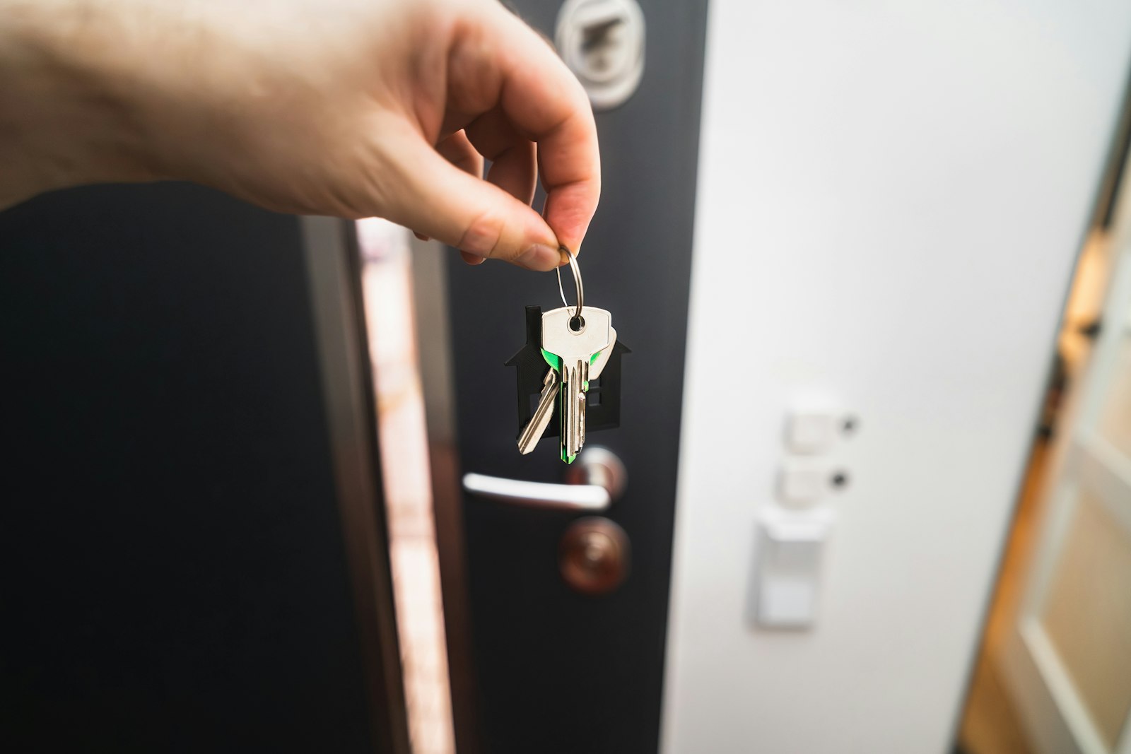 A hand holding a single key in front of a door