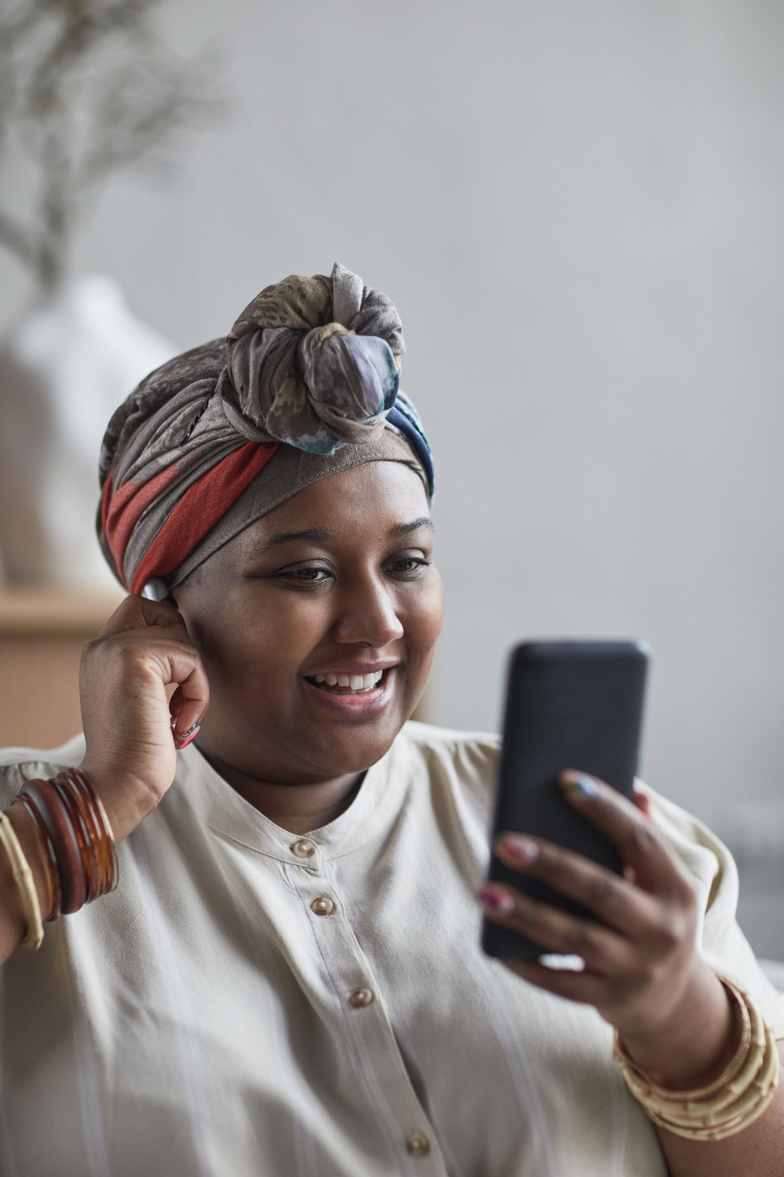 A woman in a headwrap looking carefully at her phone