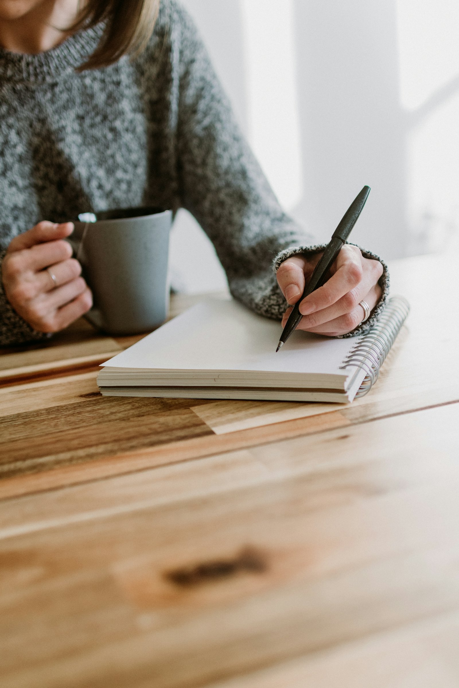 A person at a table weighing financial options with a notebook and tea