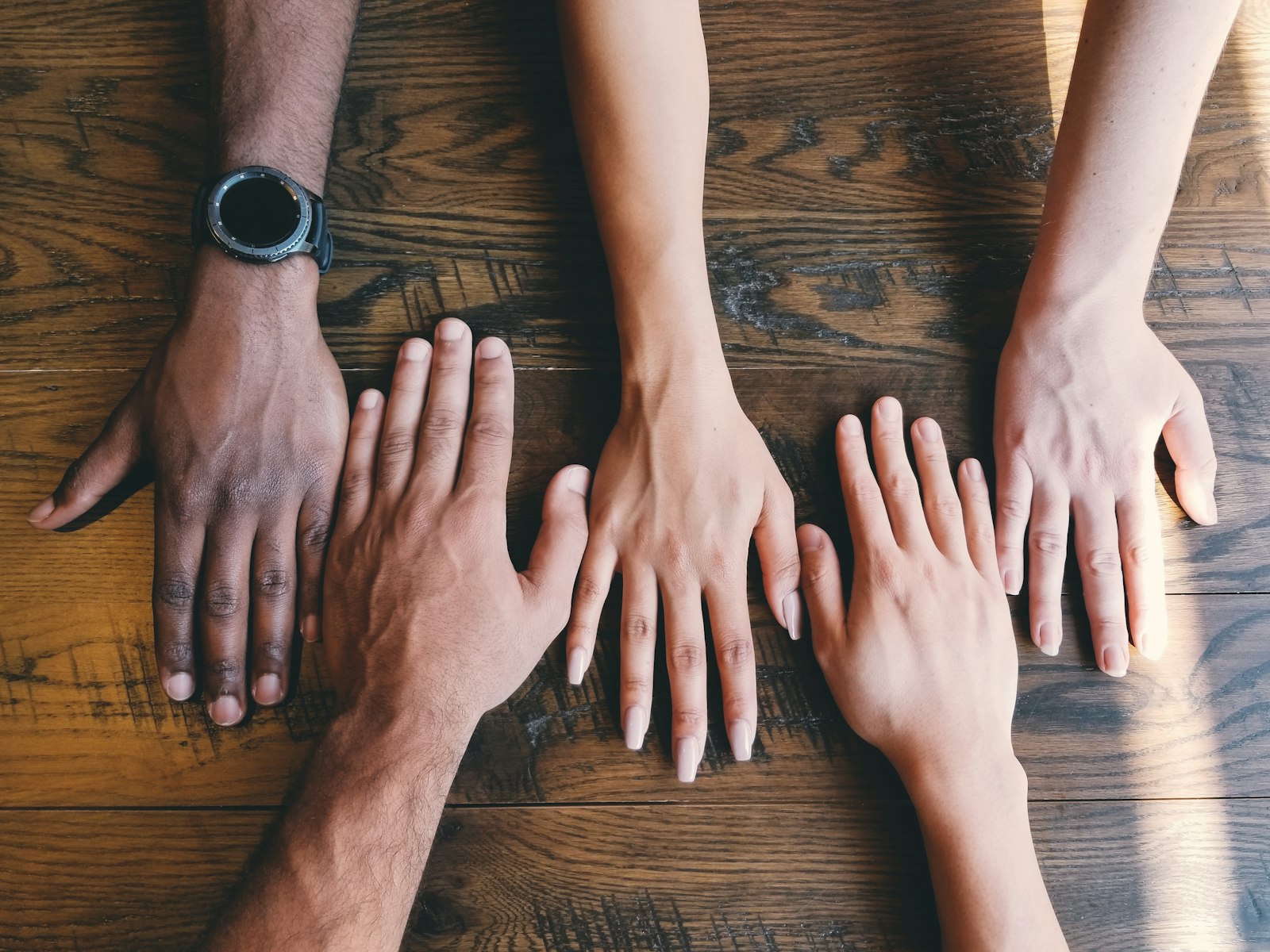 Multiple hands joined together on a shared surface, symbolizing collective trust